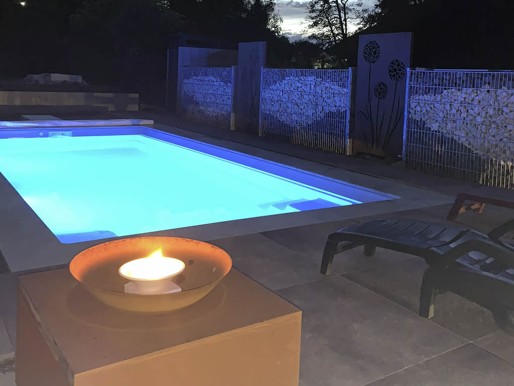 Pool in blaues Licht getaucht mit Feuerstelle