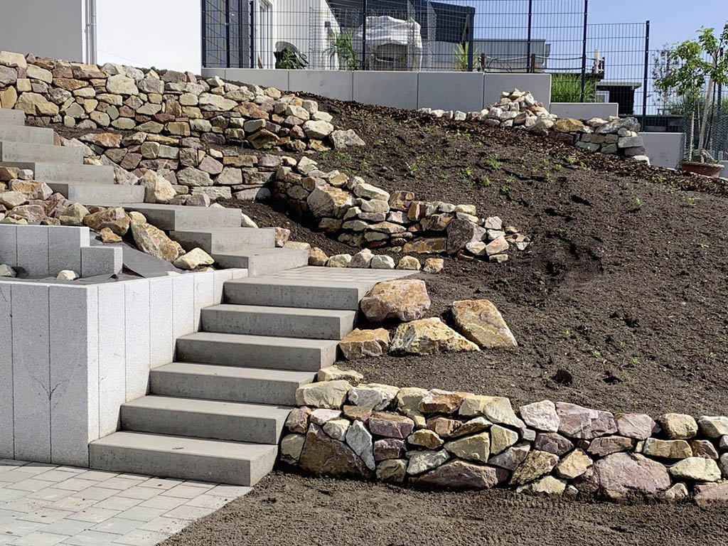 Betonblockstufen mit Granitpalisaden und Trockenmauer