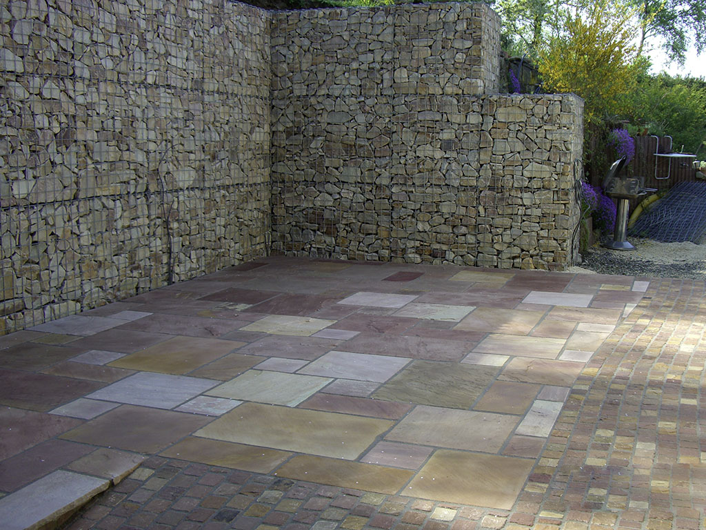 Mauer aus Gabionen mit Sandsteinplatten als Terrasse
