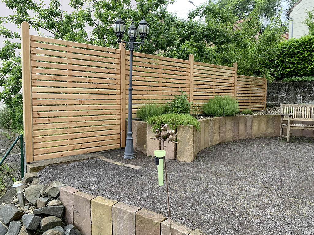 Hochbeet aus Sandsteinpalisaden und Holzsichtschutz 